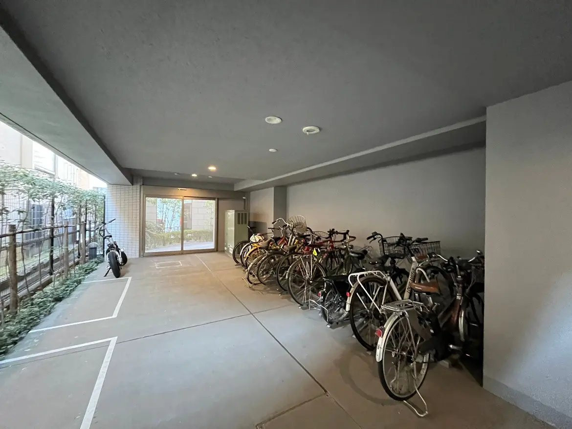 駐輪スペースがあるマンションの共用エリア、自転車が整然と並べられ屋根付きで雨風をしのげるデザイン
