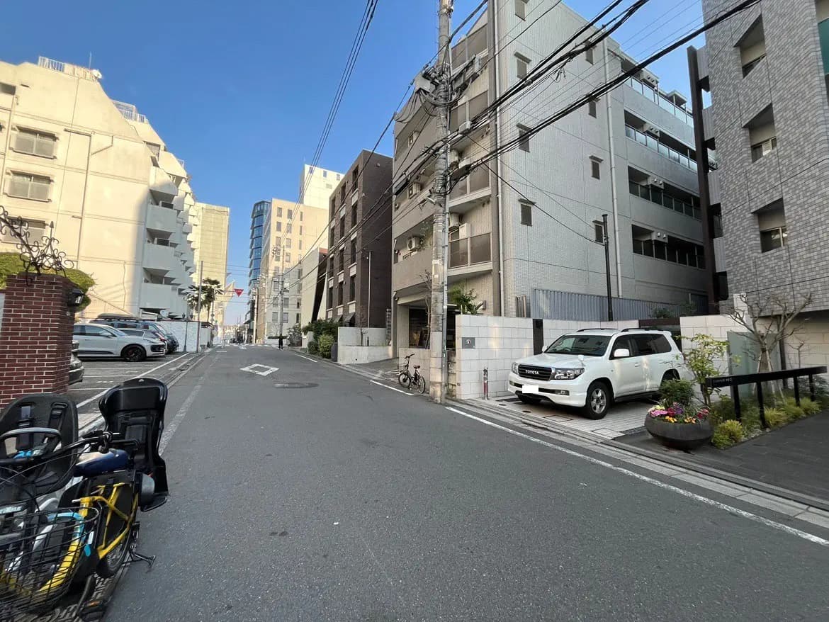 日本の都市部の閑静な住宅街の通り、晴れた日に撮影された建物と駐車されている車