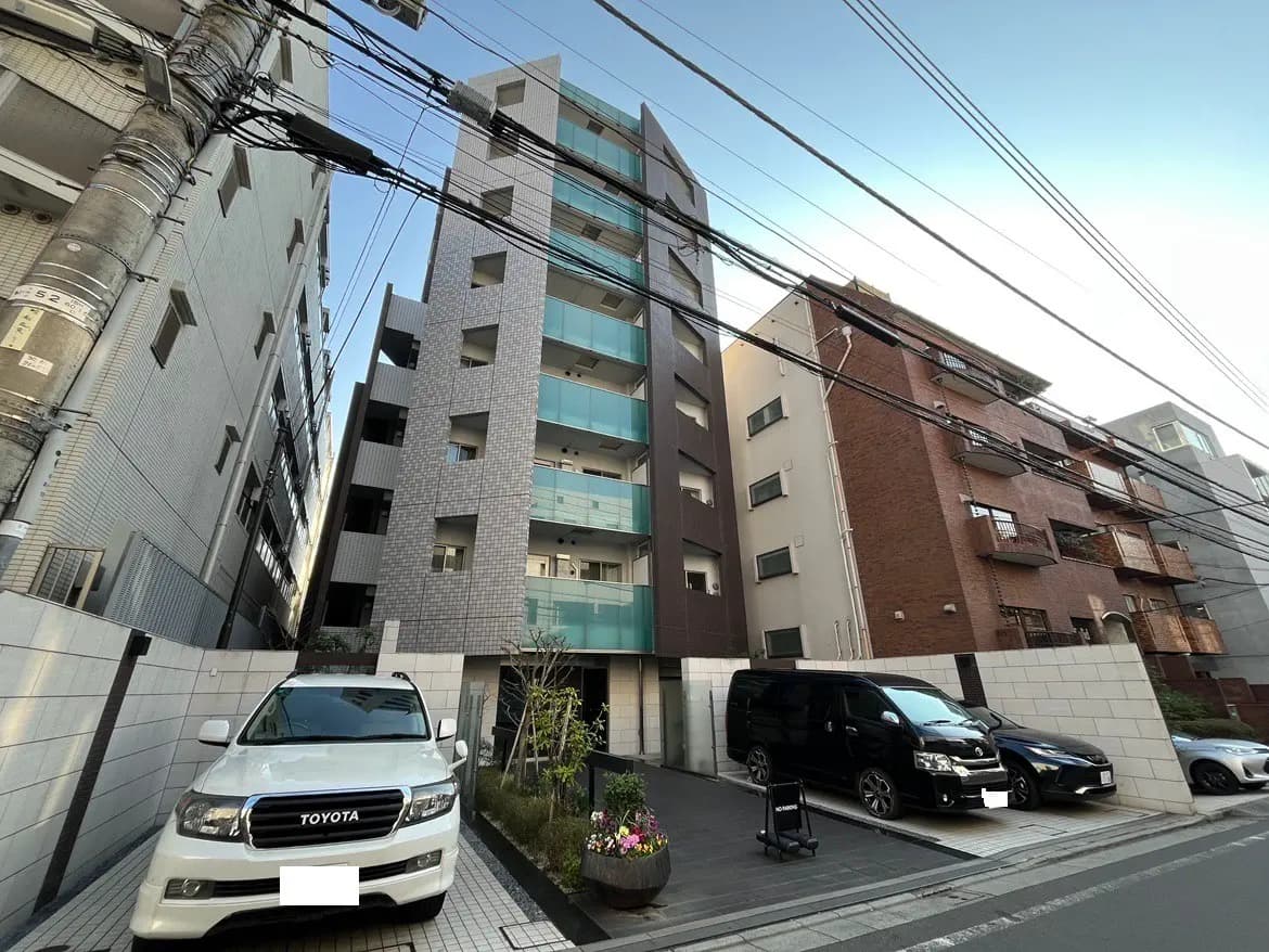 狭い通りにある現代的なマンション、駐車場には数台の車、都市部の住宅環境