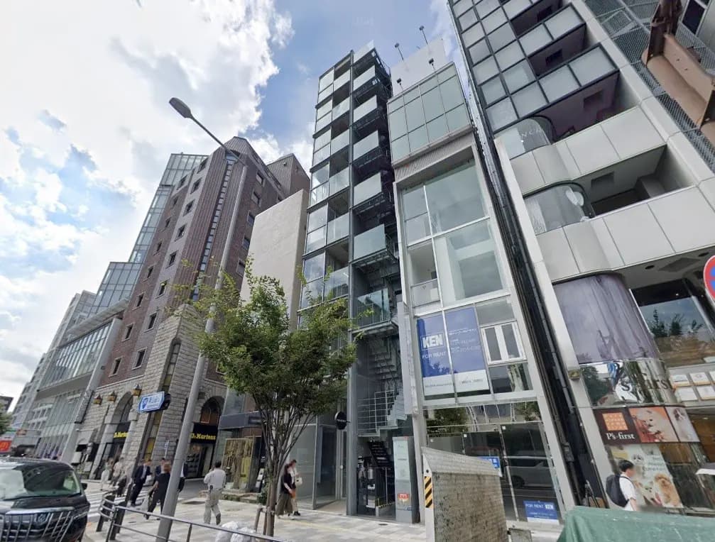 都会の通りに並ぶモダンな建物のファサード、歩行者と車が通る光景