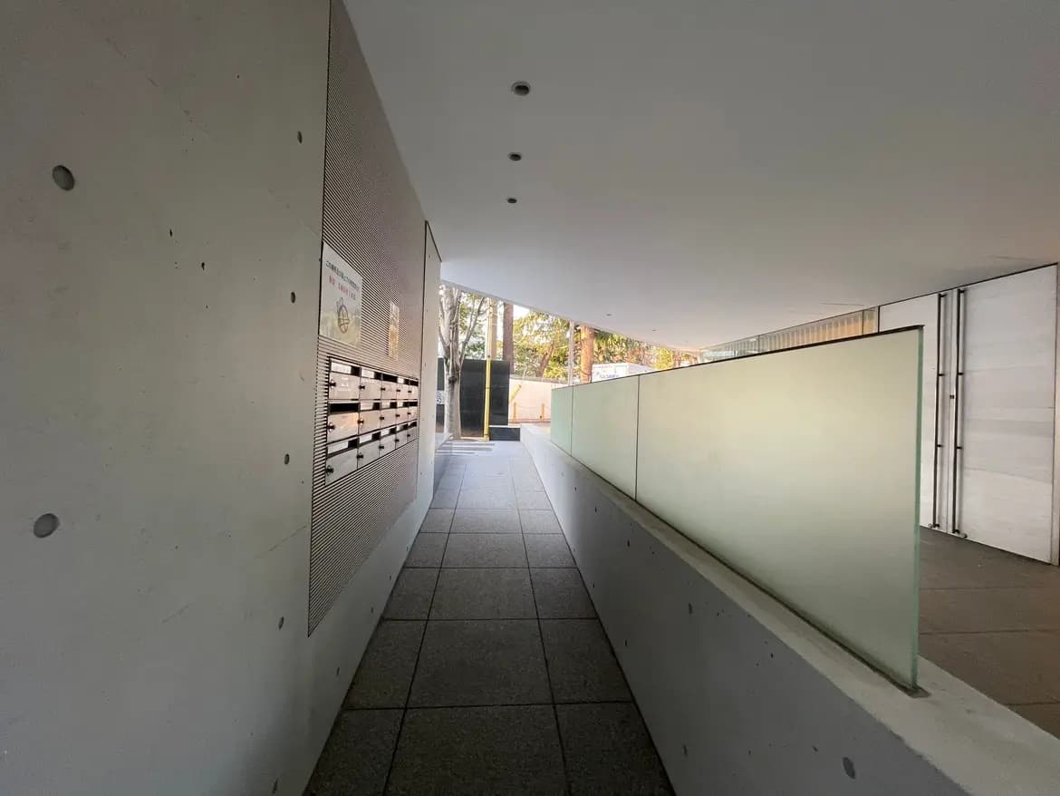 モダンな建物のエントランス、壁面に取り付けられた郵便受け、クリアなガラスの手すり