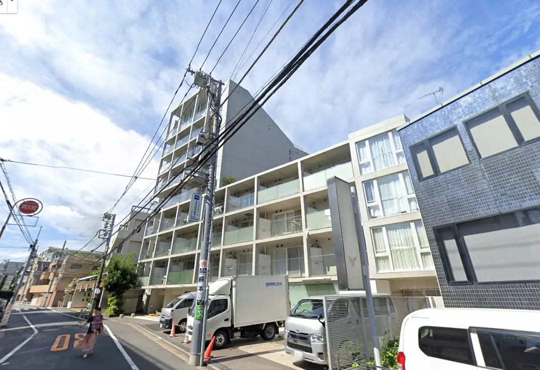都会の住宅街に建つモダンなマンション、青空と電線が見える景色