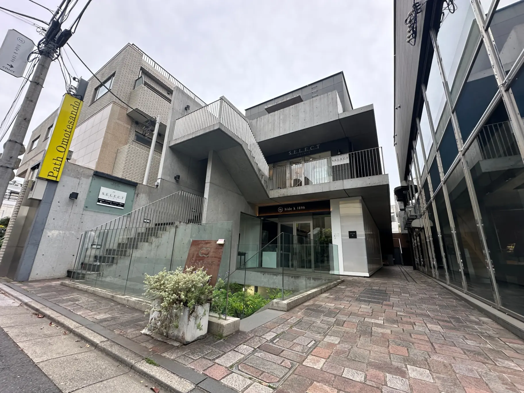 モダンで個性的なデザインの建物、コンクリートの外壁、商業施設のエントランス、ガラスの手すりが特徴