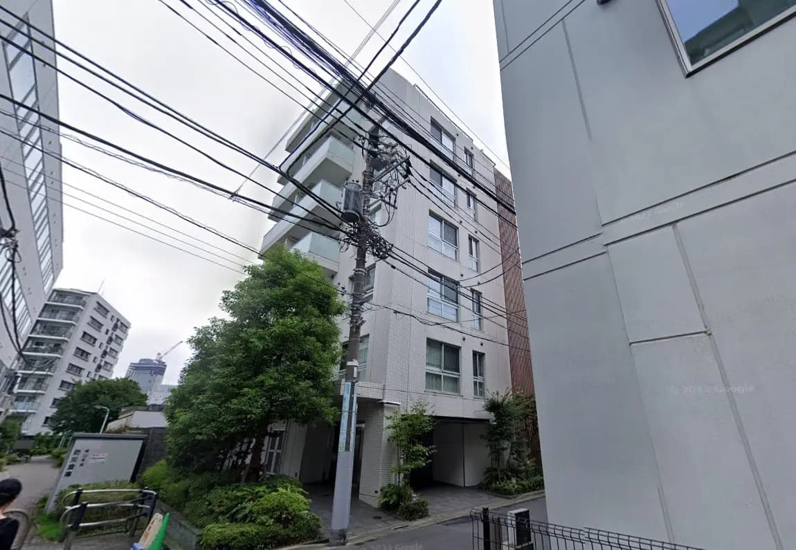緑豊かな植栽に囲まれた都心のモダンな白いマンション、電柱と電線が絡まる都市風景