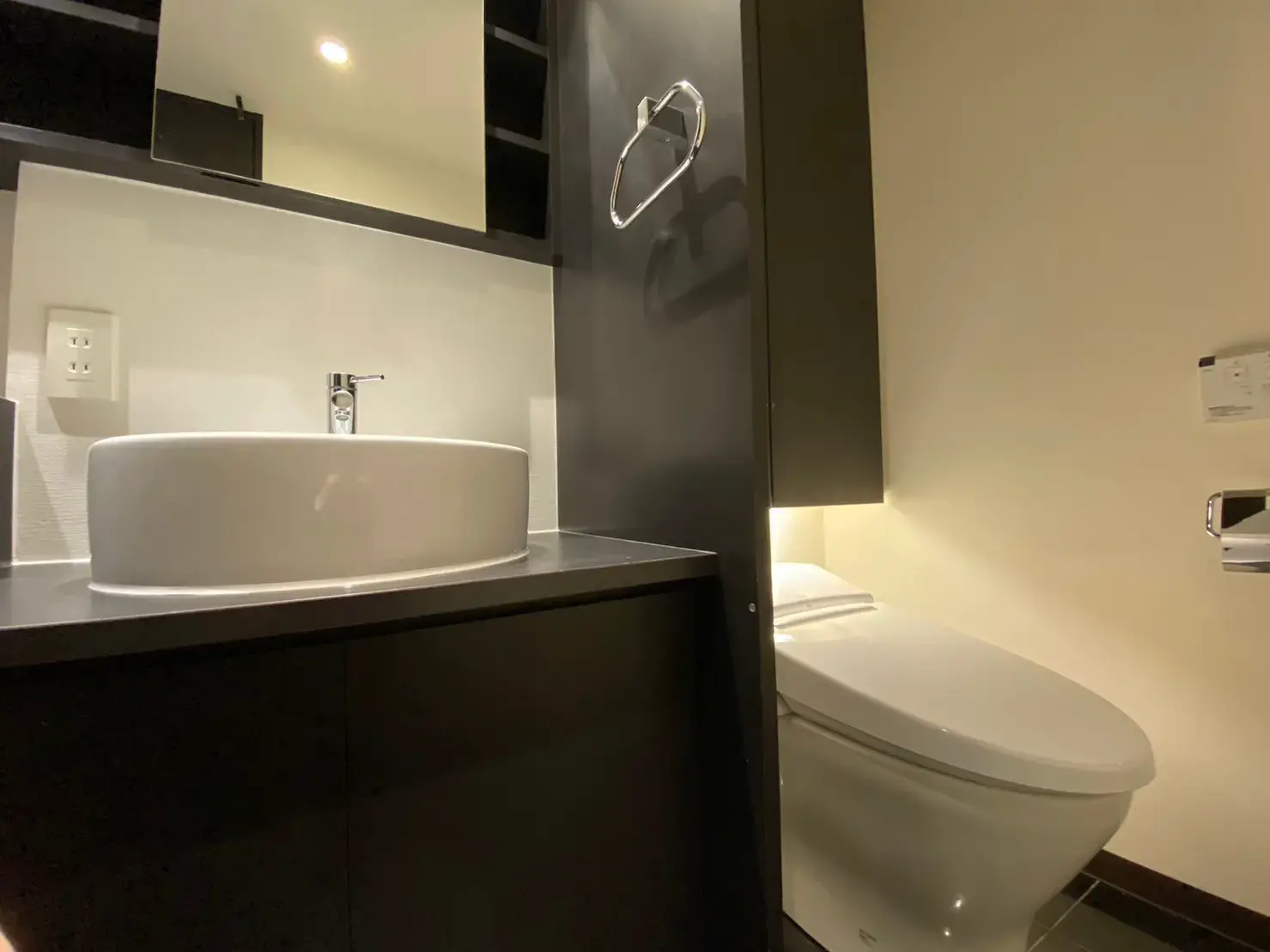 モダンなデザインのバスルーム、上部のライトが照らす洗面台とトイレのインテリア