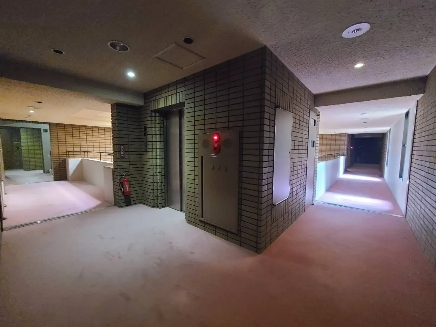 モダンな建築様式のビル内部の廊下、壁面にタイル装飾、間接照明が柔らかな雰囲気を作り出すデザイン