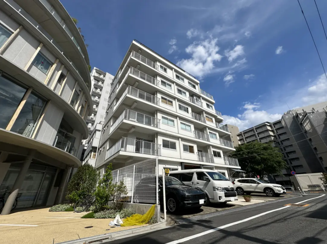 新築マンションの外観、モダンな建築デザイン、駐車場付き、晴天の日に撮影
