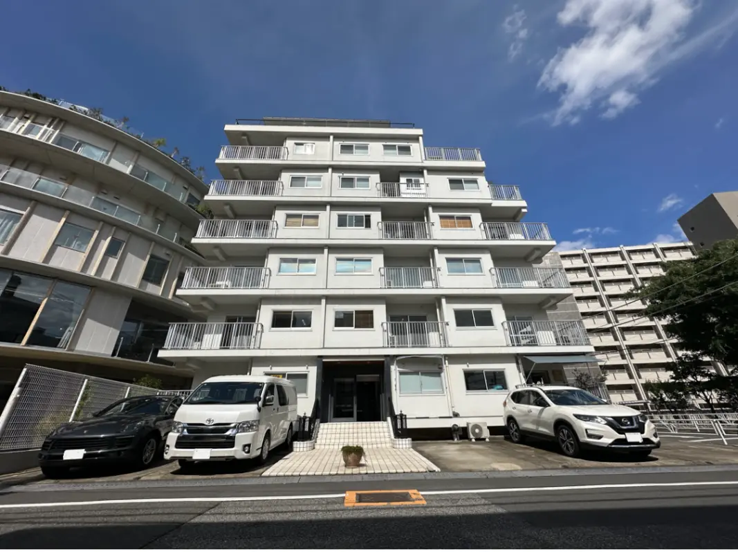現代的な外観の都市型マンション、駐車場付き、青空と雲が背景