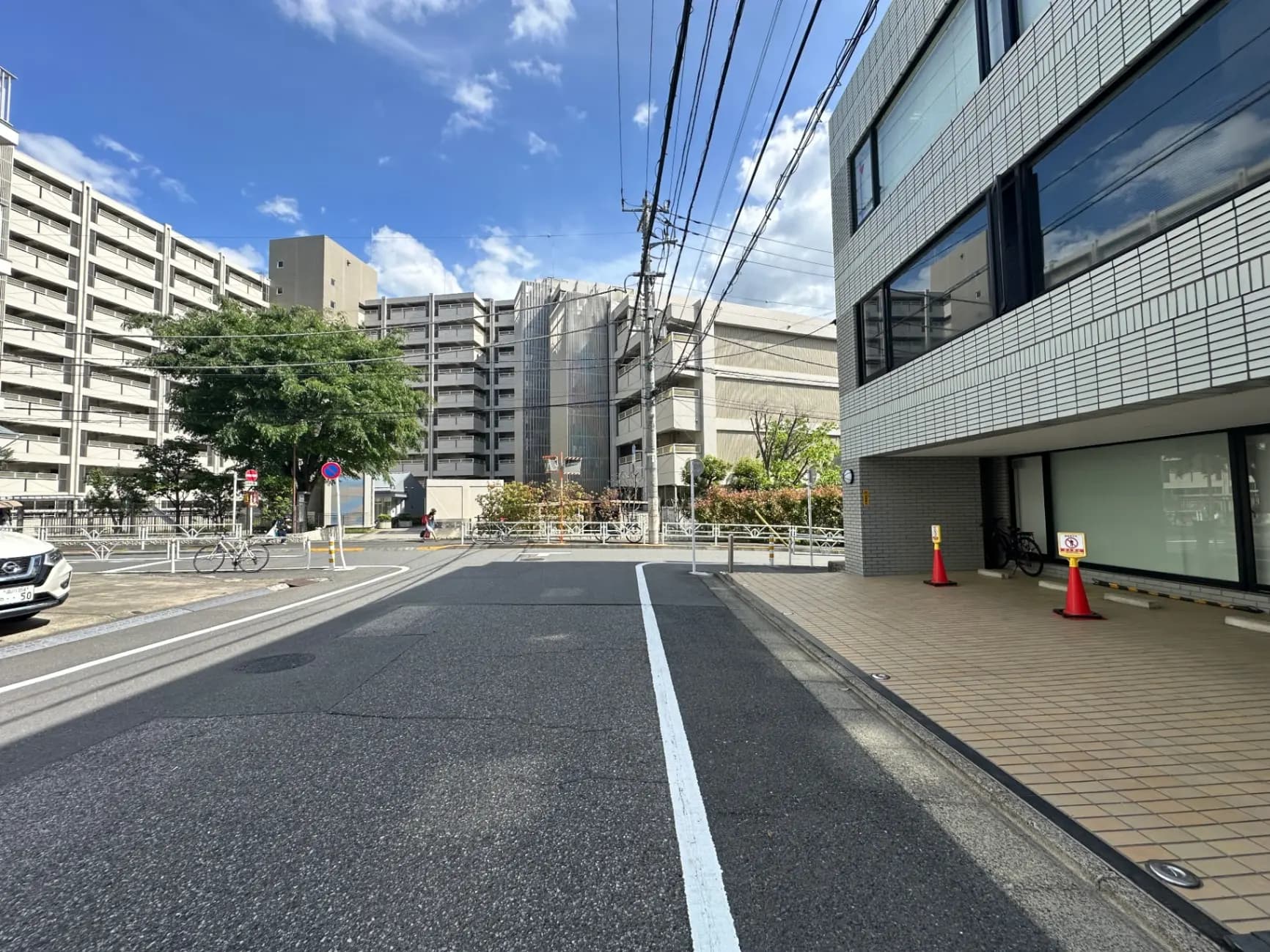 日本の都市風景、ビルとマンションが並ぶ通り、青空と電線が交差する光景