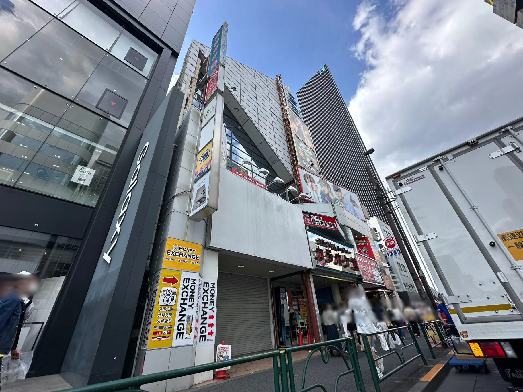 都会の通りにある建物の外観、看板、広告の写真、為替両替所のサインが目立つ