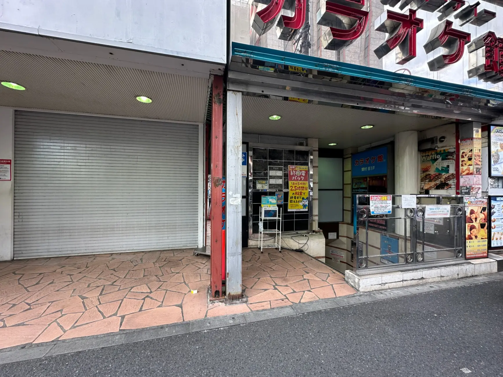 都市のビル街にある閉店した商店のシャッターと店頭に掲示されたメニュー看板