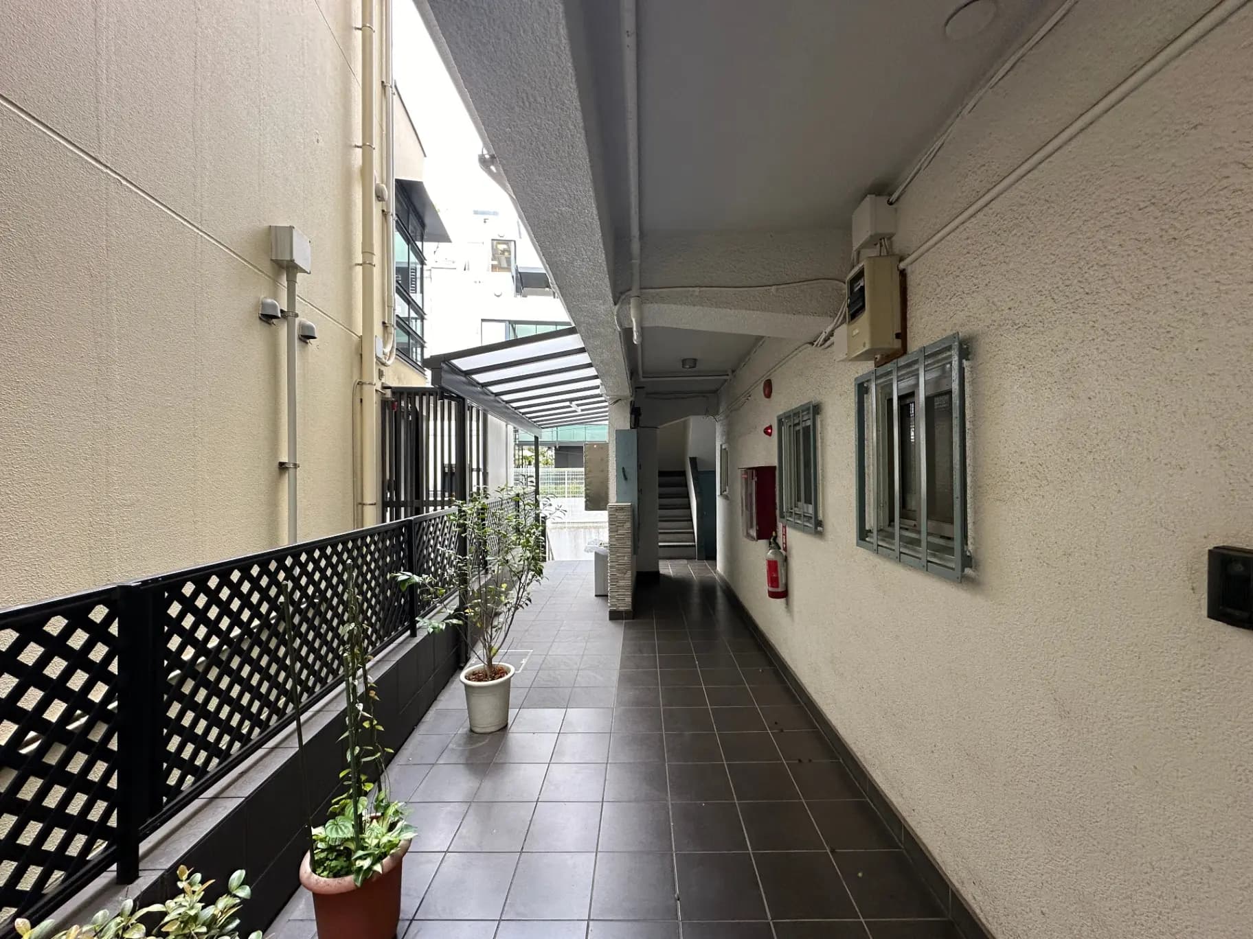 都会のマンションの共有廊下、手すりや植木鉢が配置された屋外スペース