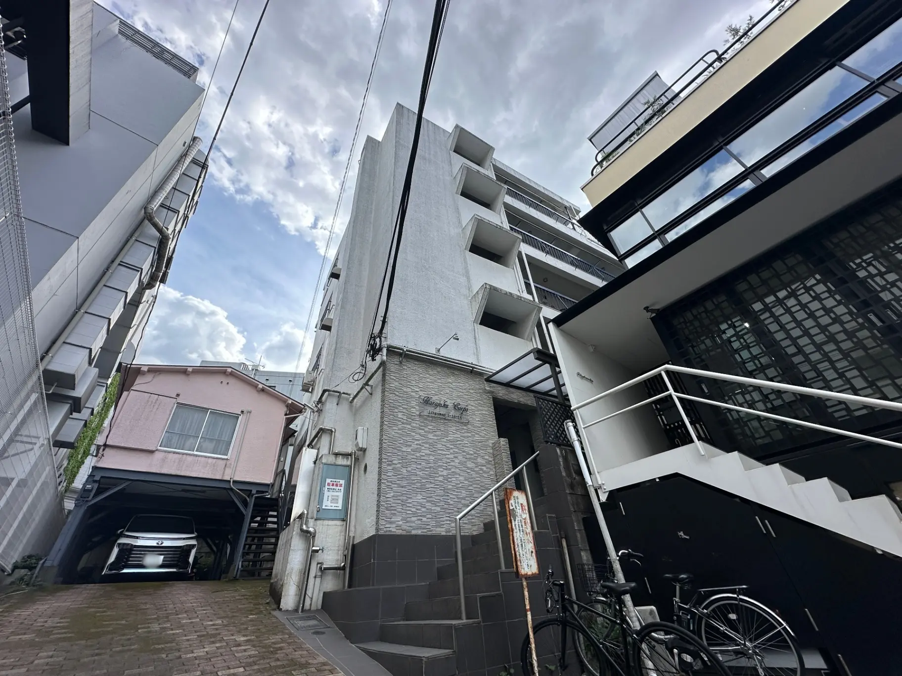狭い路地に建つ現代的なアパート、駐車場付きのピンク色の家、都市風景