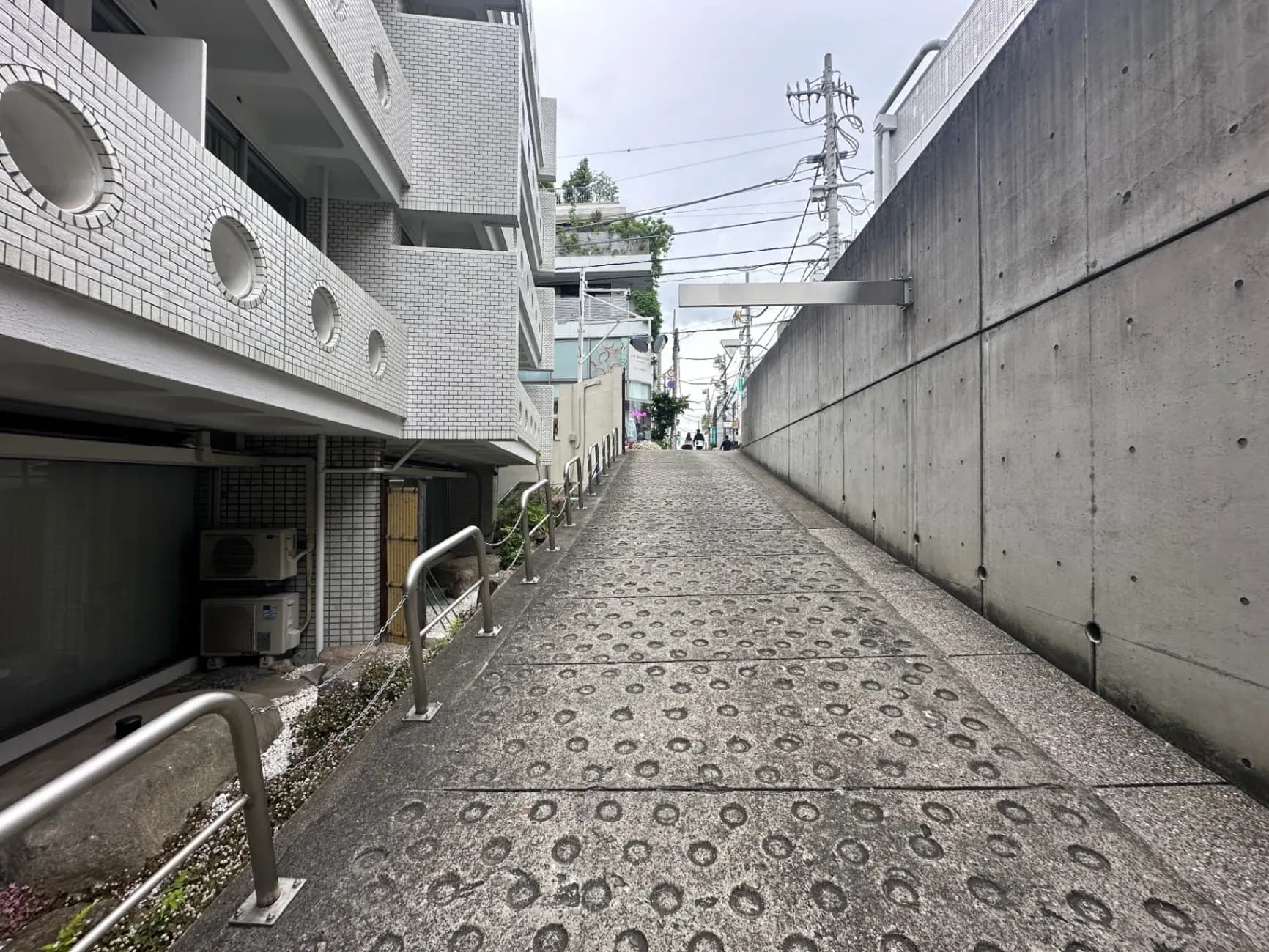 都会の坂道、コンクリートの壁と舗装された道路、白い建物の外観