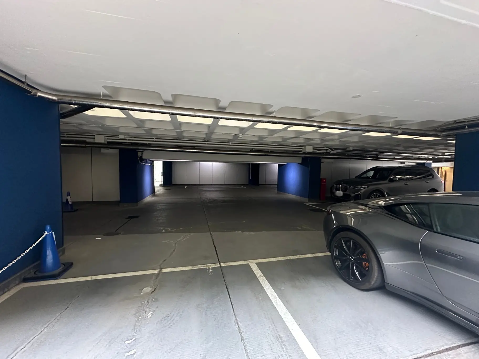 広々とした地下駐車場、灰色のスポーツカーと白いSUVが駐車中