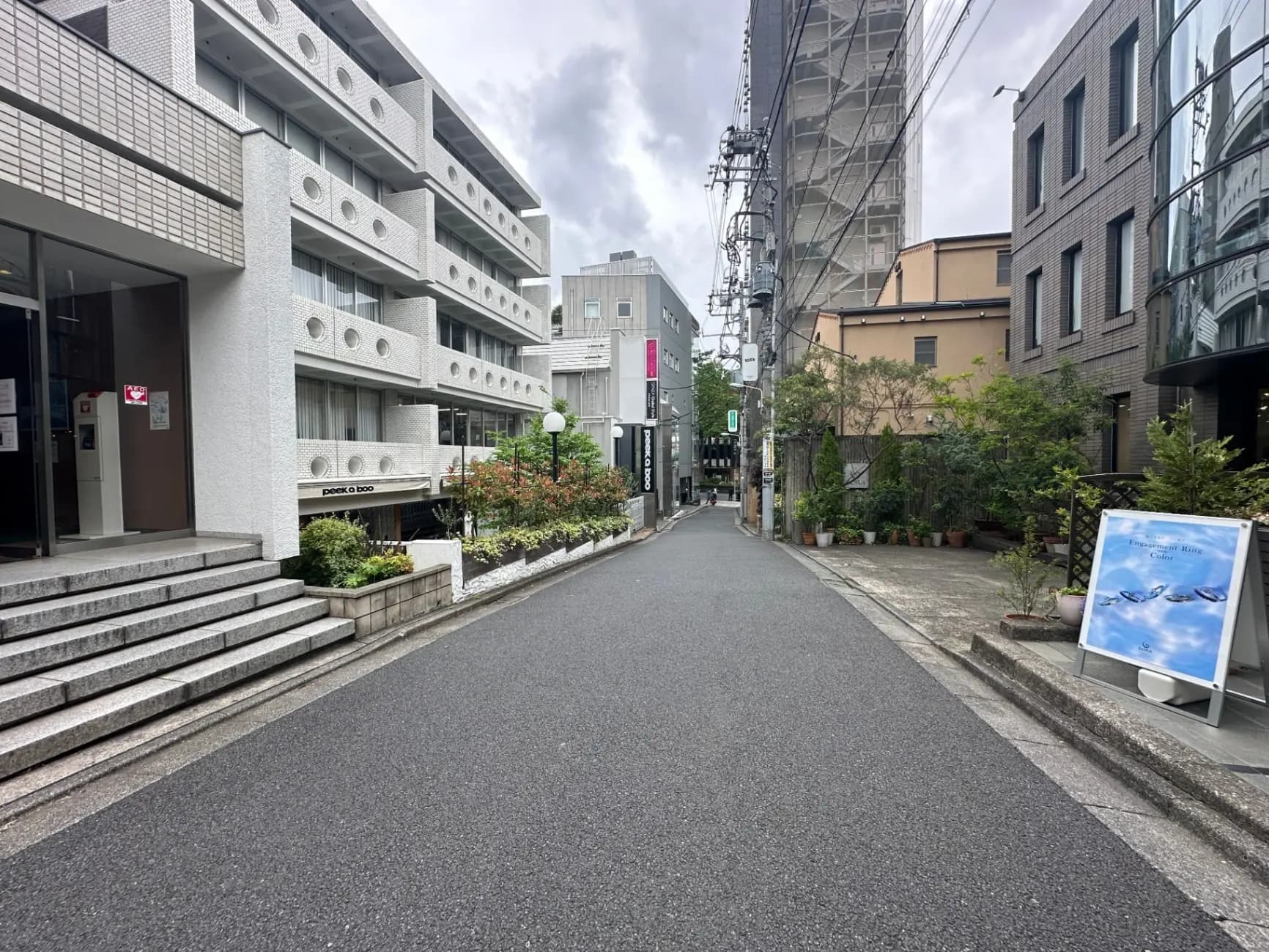 静かな都市の住宅街、モダンな建物と植木がある歩道、くもり空