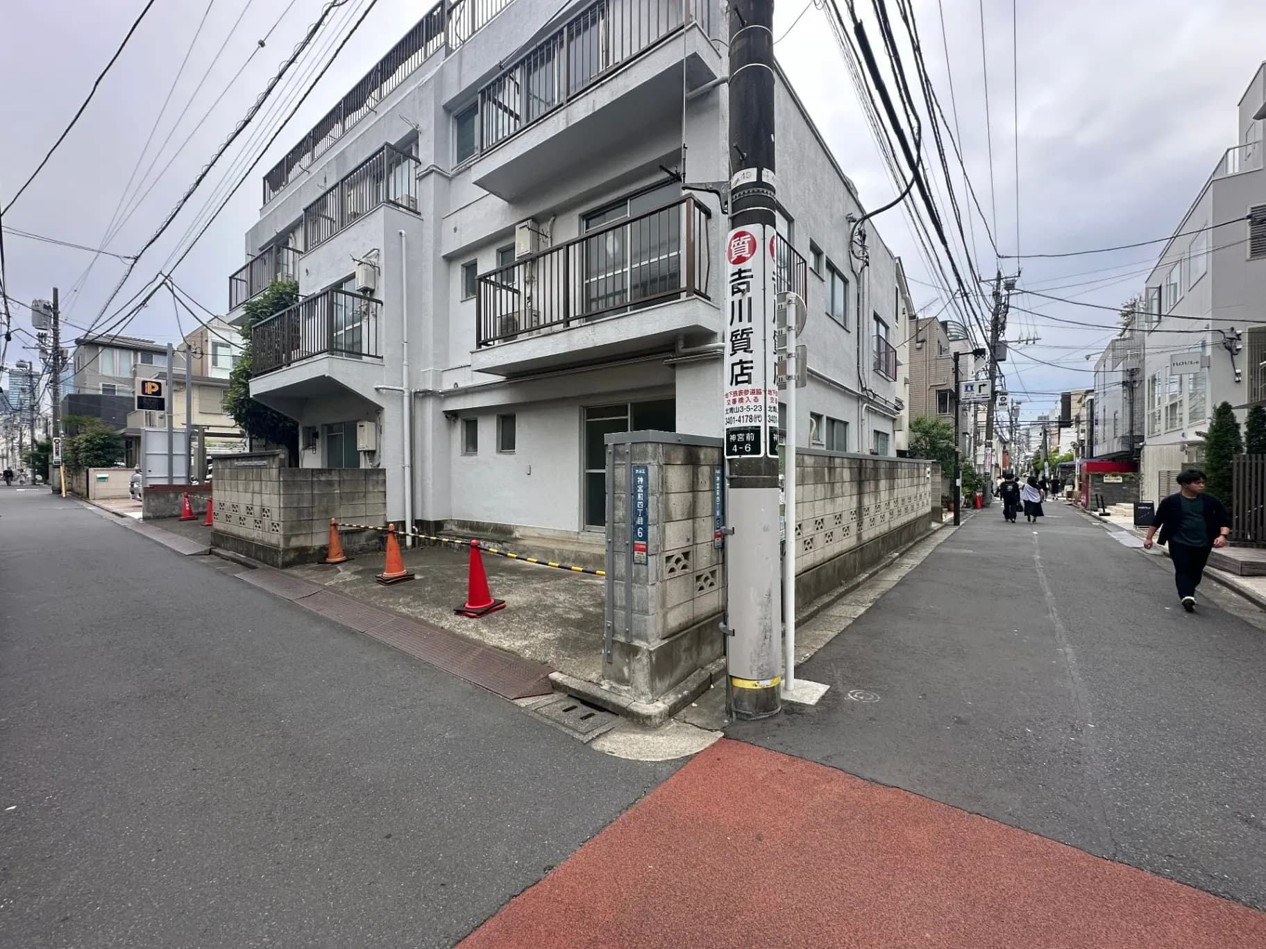 日本の都市の住宅街の景色、歩道と通り、アパート建物の外観、配電線と駐車場の看板が見える