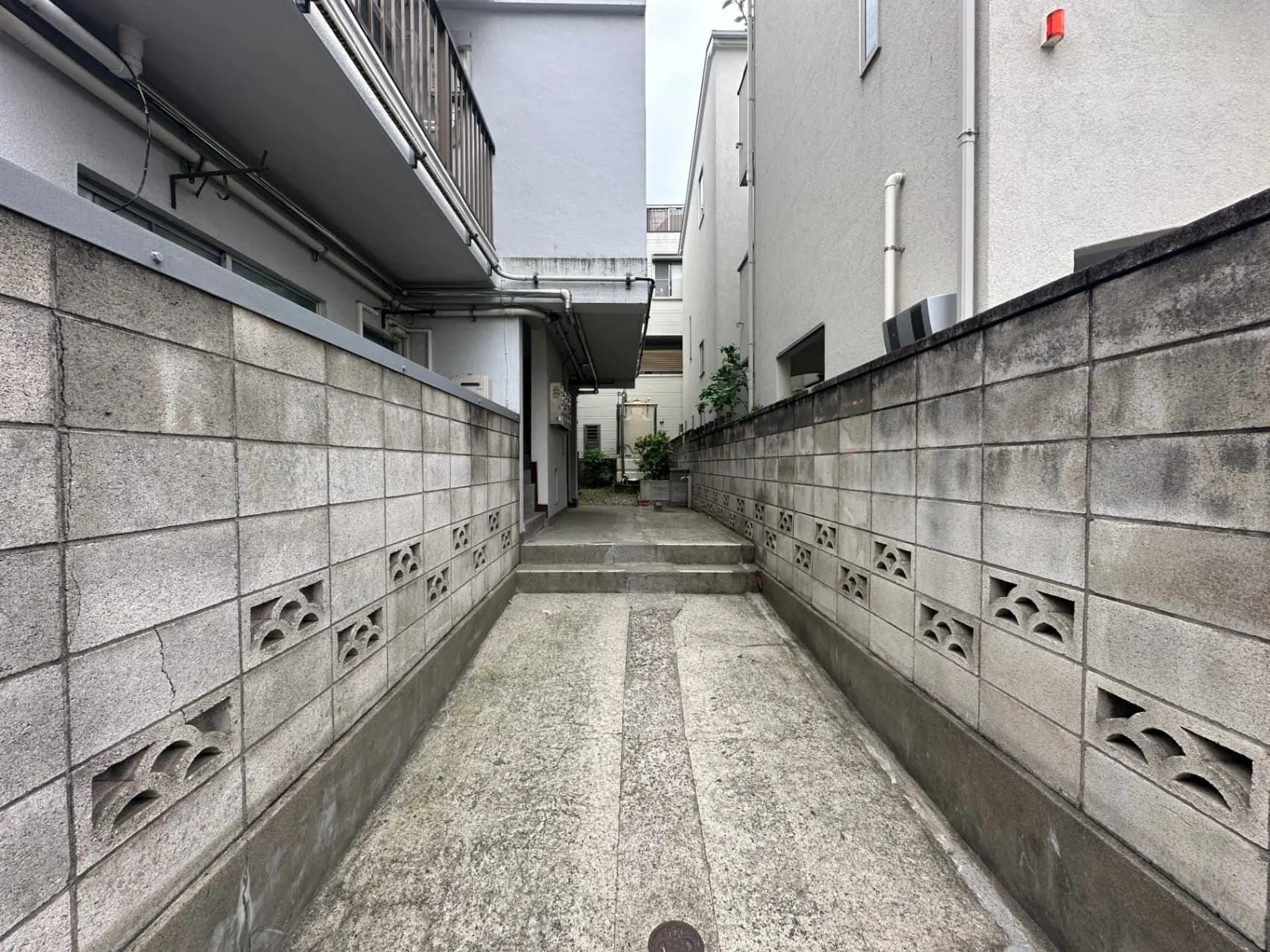 日本の住宅地の狭い通路、コンクリートブロックの壁と階段、都市の住まいの外観