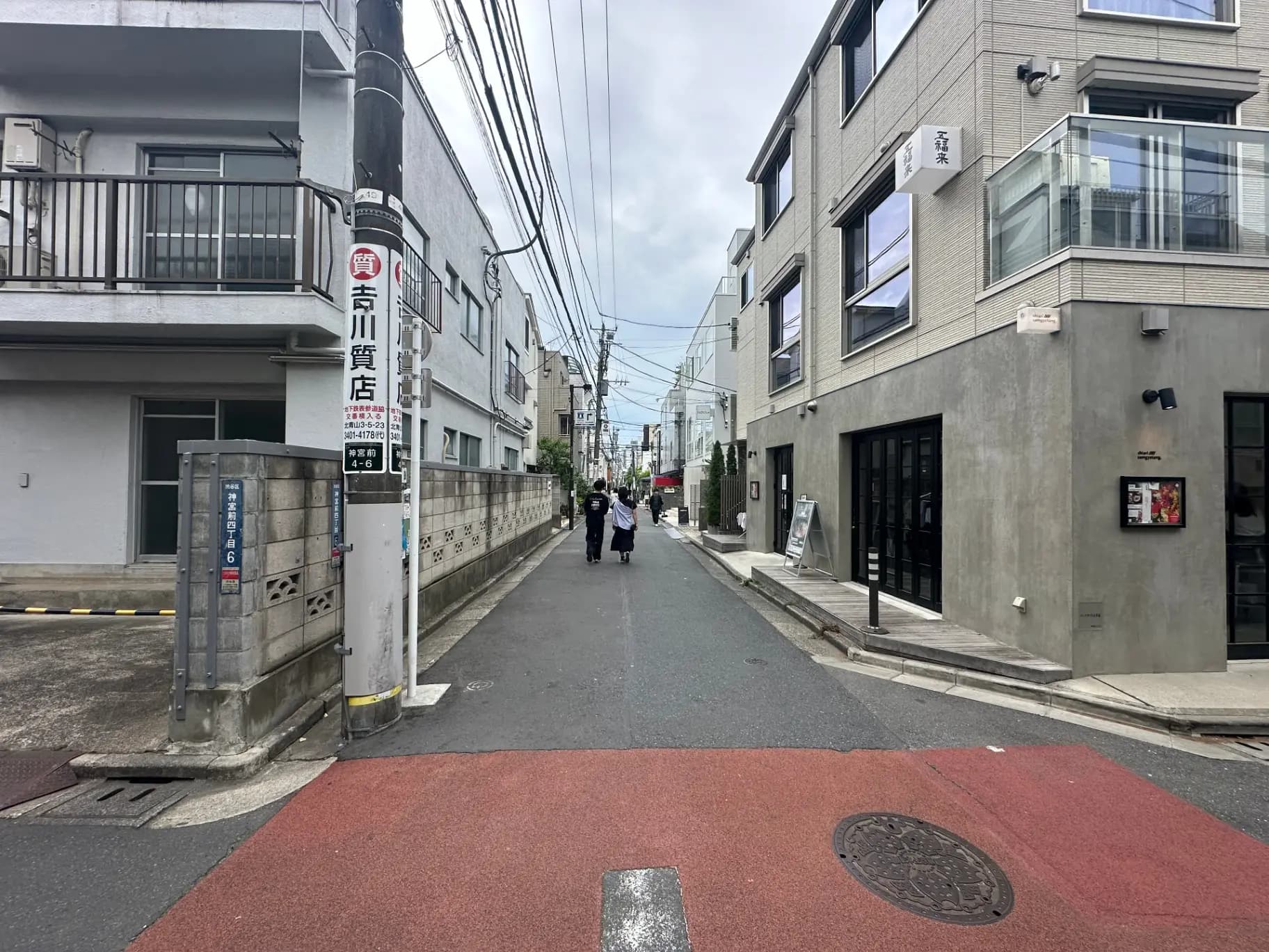 都市の住宅街、モダンな建物と路地、通行人と電信柱の風景