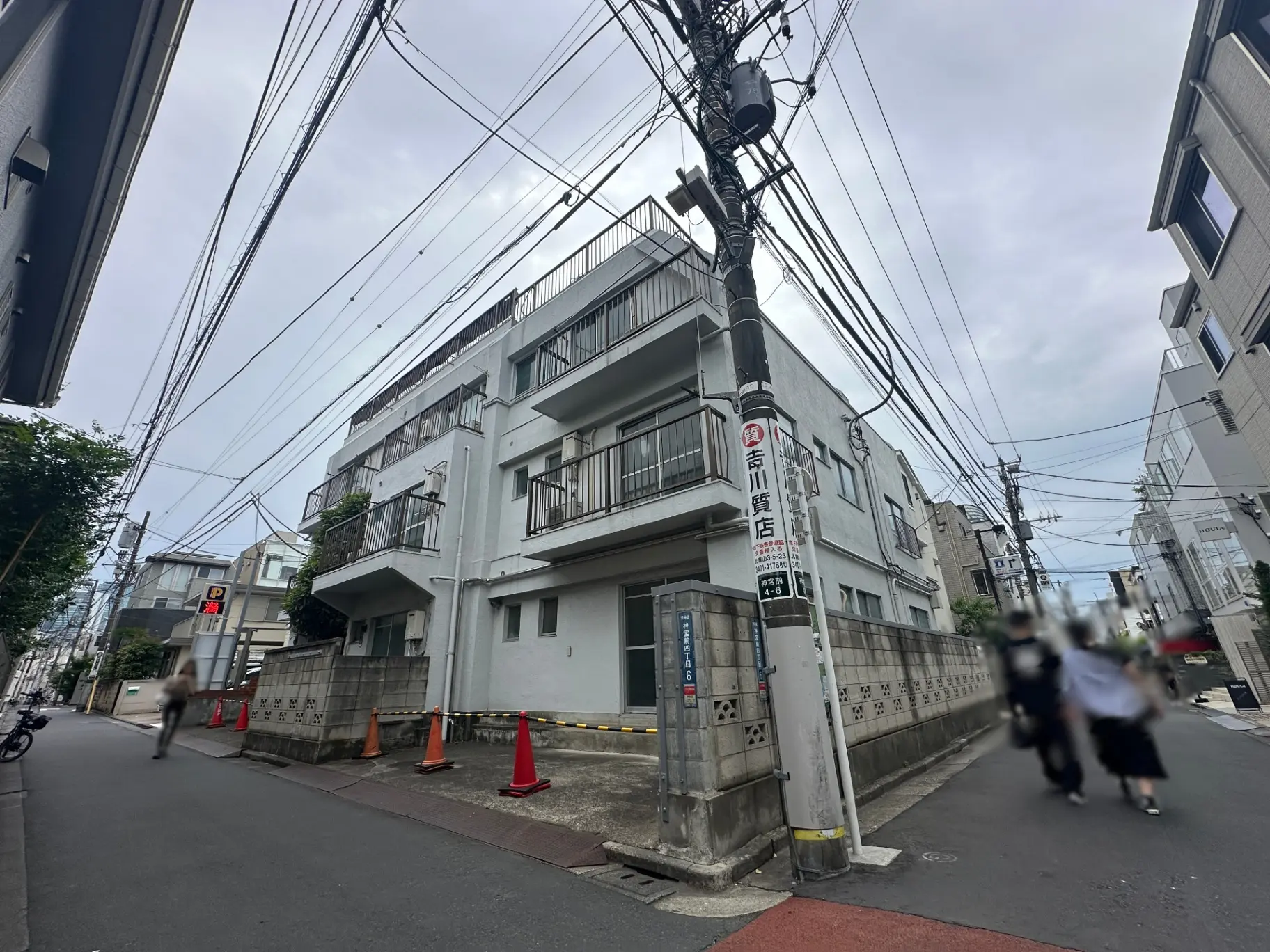 都会の住宅街の風景、電柱と多くの電線、歩道には自転車と歩行者