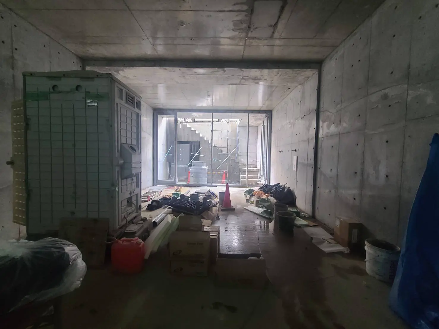 工事中の建築現場、コンクリートの壁と床、散らばった建築資材と工具