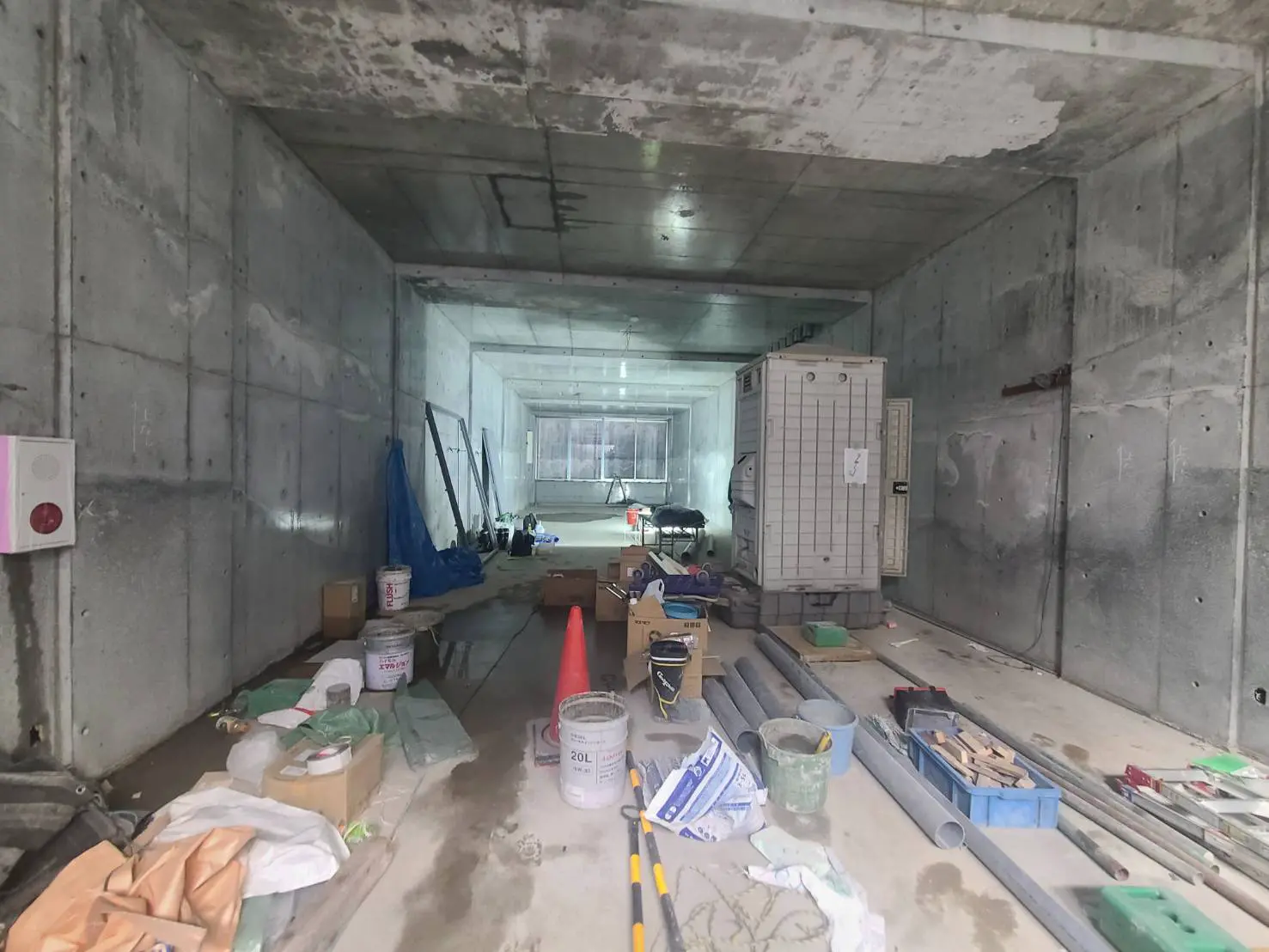 工事中の建築現場、コンクリートの壁と床、建設資材と道具が散乱