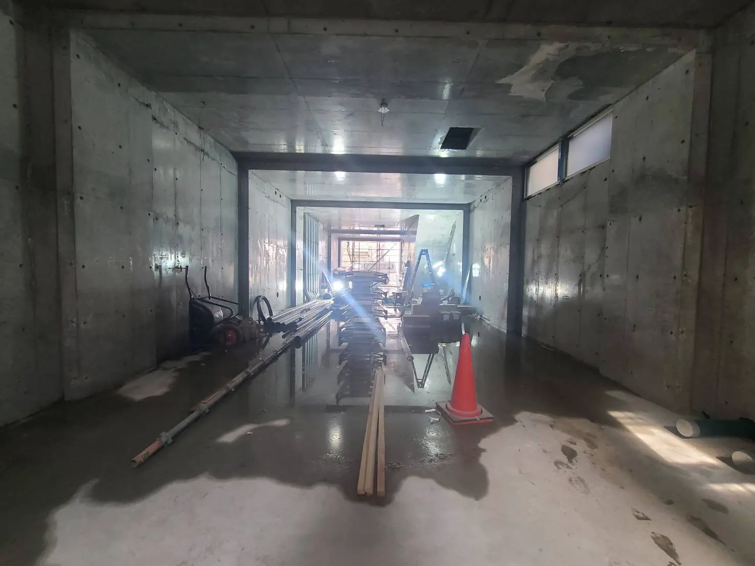 建設中のコンクリート構造の建物内部、作業材料と工具が並ぶ廊下