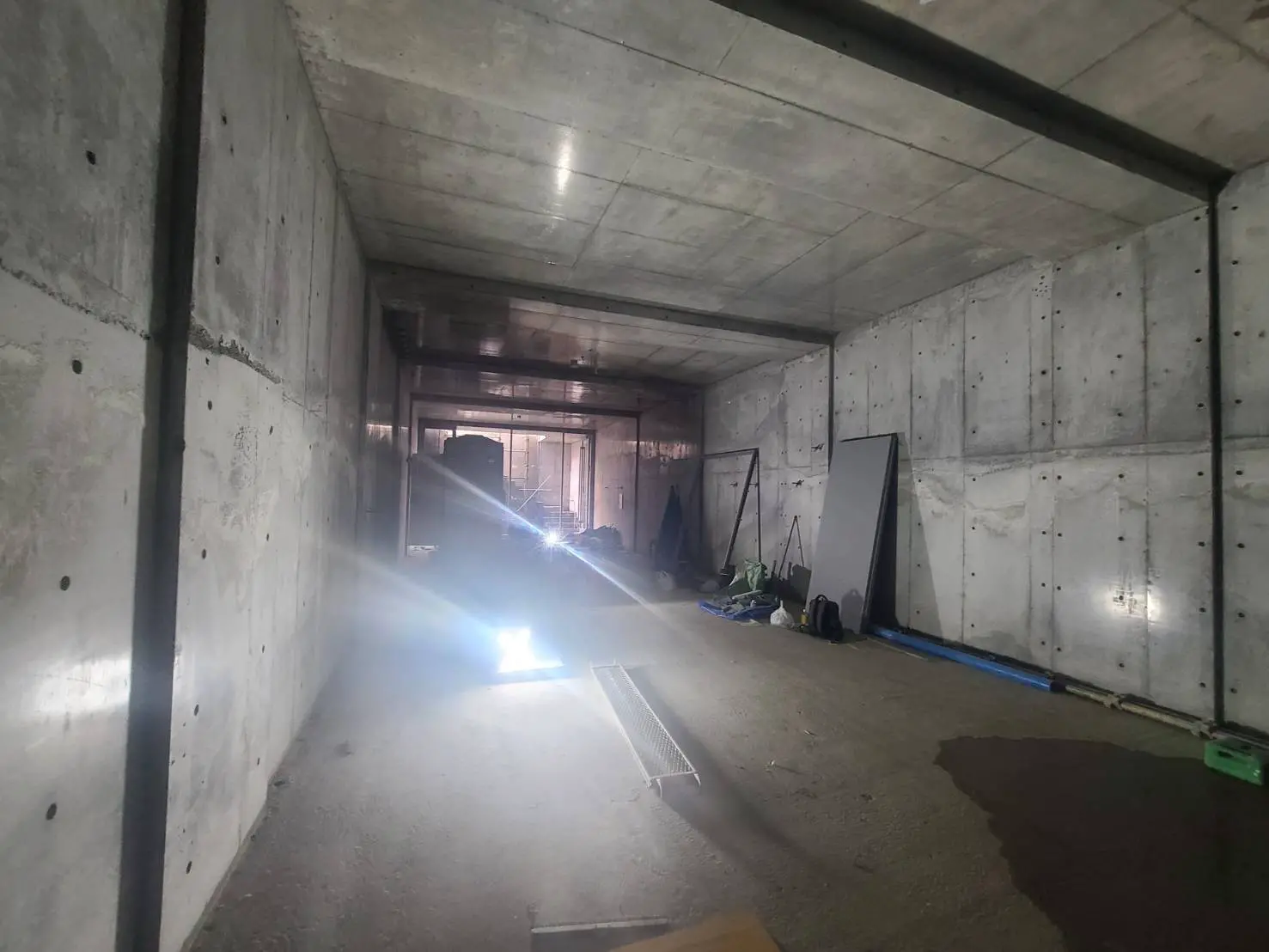 建設中のコンクリート構造物内部、未完成で照明の下作業用具が見える状況