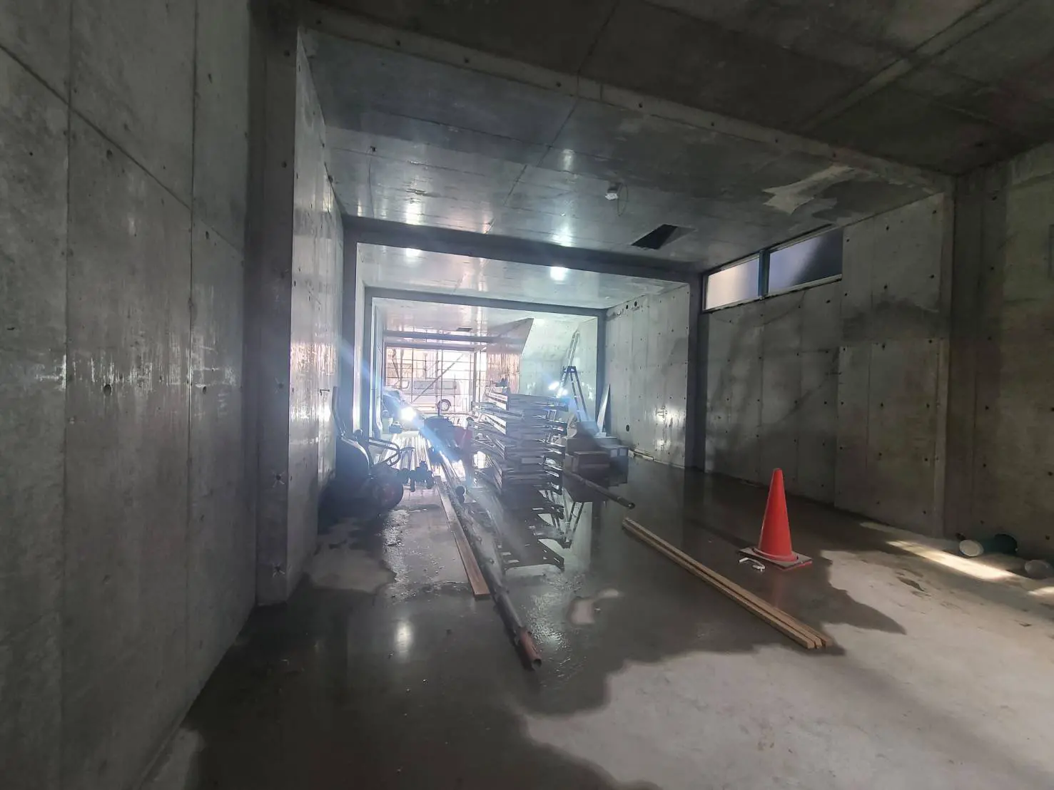建設中のコンクリート構造のビルの内部、散らかされた工事用材料と足場、自然光が差し込む窓