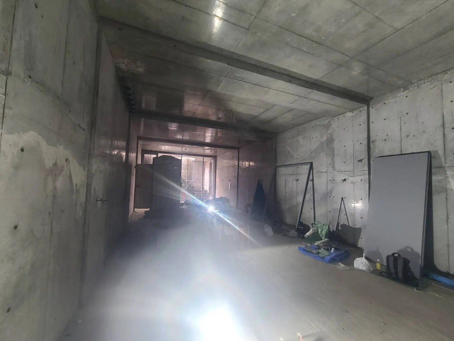 未完成の建物内部、コンクリートの壁と天井、工事資材が散らばる現場