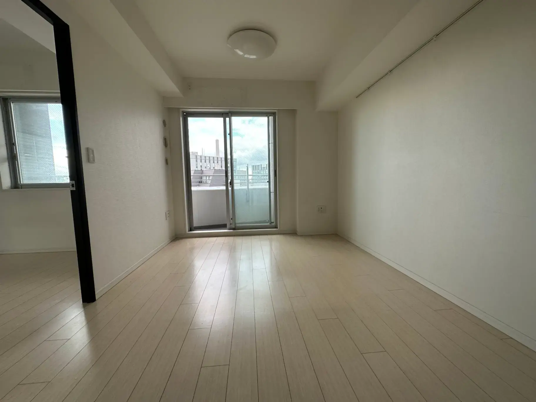 明るく広々とした空の部屋、木製フロア、バルコニーつき