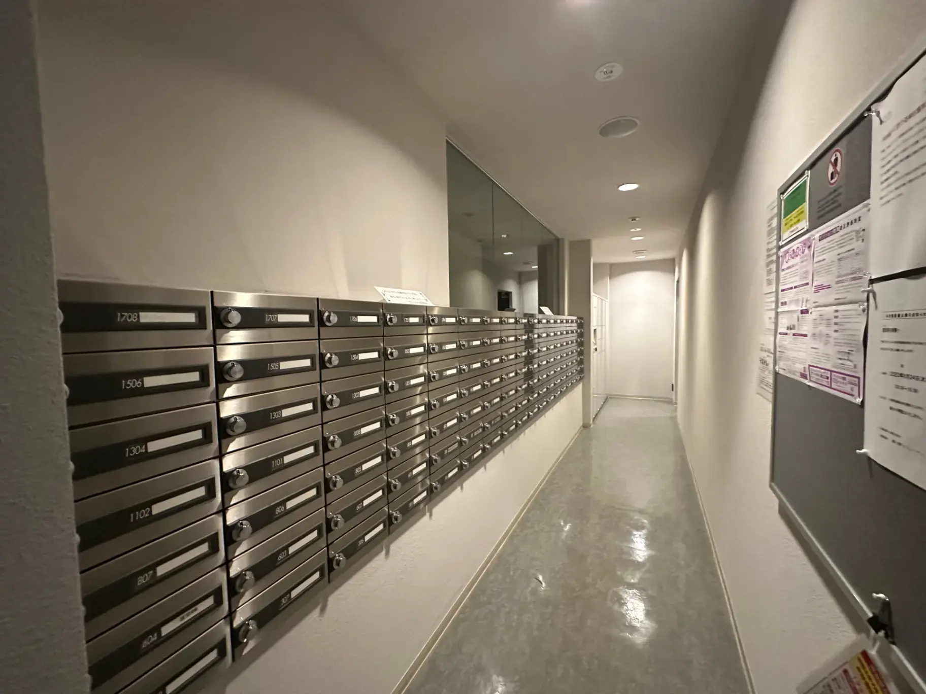 マンションの室内に設置された多数の郵便受け、白い壁と清潔感のある廊下デザイン
