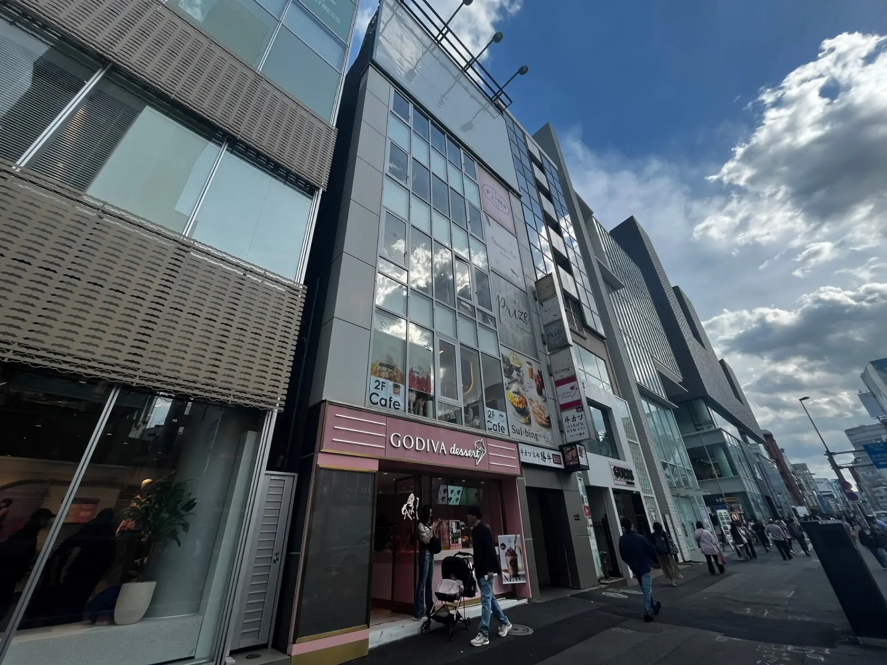 都市型モダンなビル群、ゴディバチョコレート店の外観、歩行者通りと青空