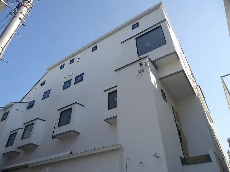 - 白い外壁の現代的な建物、特徴的な出窓と青空を背景にした高層住宅の外観
