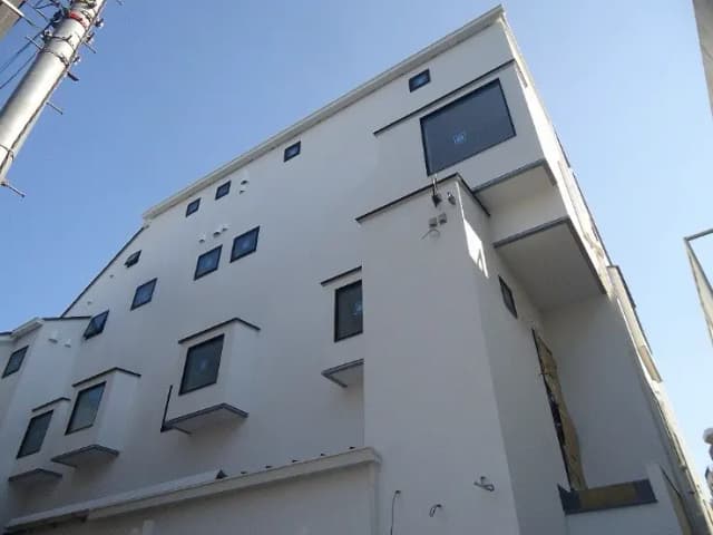- 白い外壁の現代的な建物、特徴的な出窓と青空を背景にした高層住宅の外観