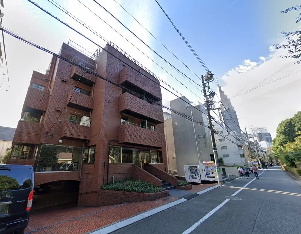レンガ造りの外観が特徴的なマンション、都会的な雰囲気の住宅街、駐車場入り口と歩行者の様子
