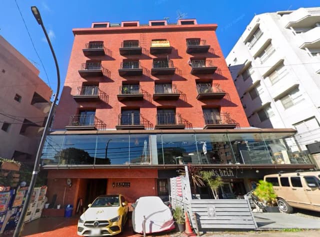 都市の中心部に位置する赤レンガ造りのマンション、透明なガラス張りの店舗がある建物の外観