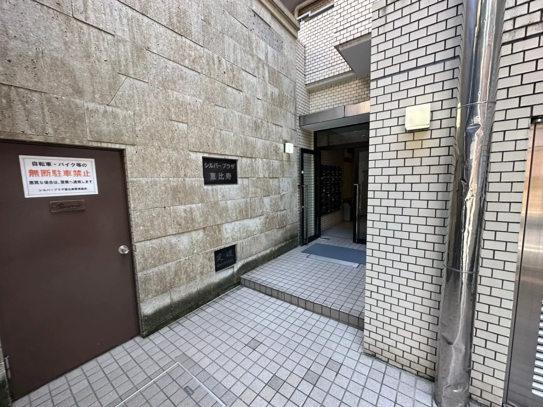 ビルの外観、煉瓦とタイルの壁、案内板と入口のある都市の通り