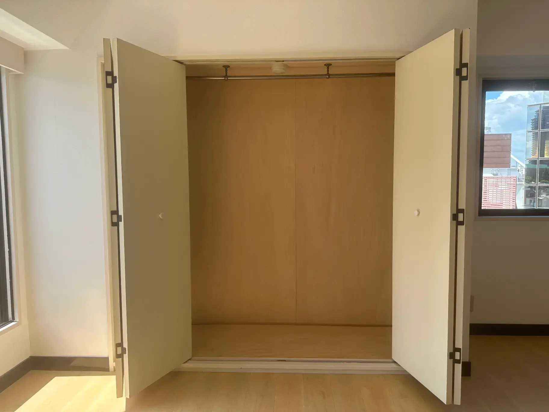明るい空間のクローゼット付きの空の部屋、床はラミネート仕上げ、自然光が入る窓