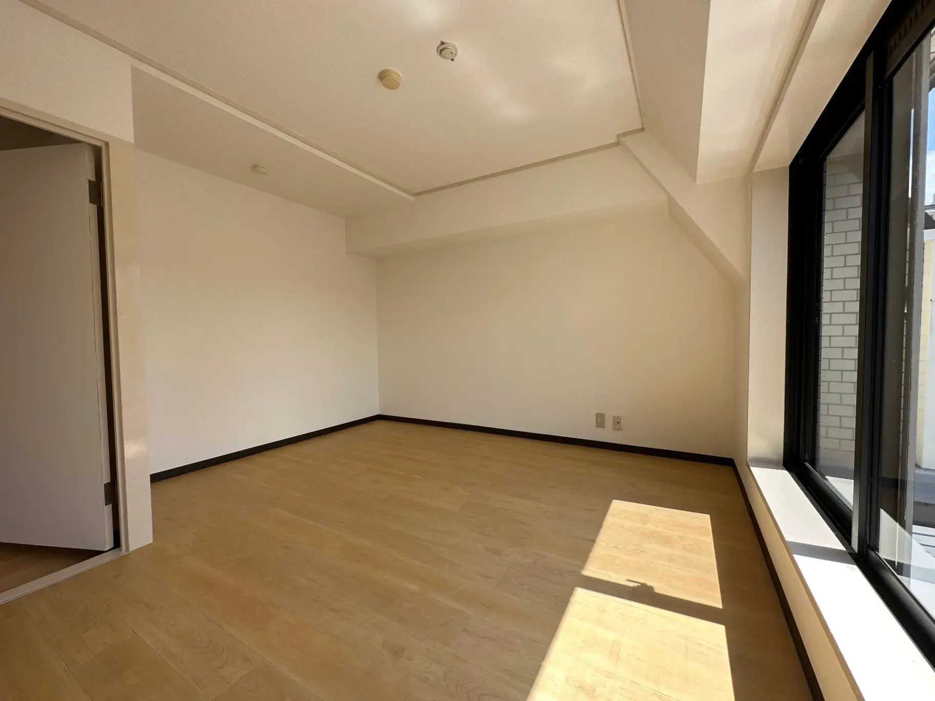 空白の壁と床、天井に埋め込み型照明がある明るい空間と大きな窓