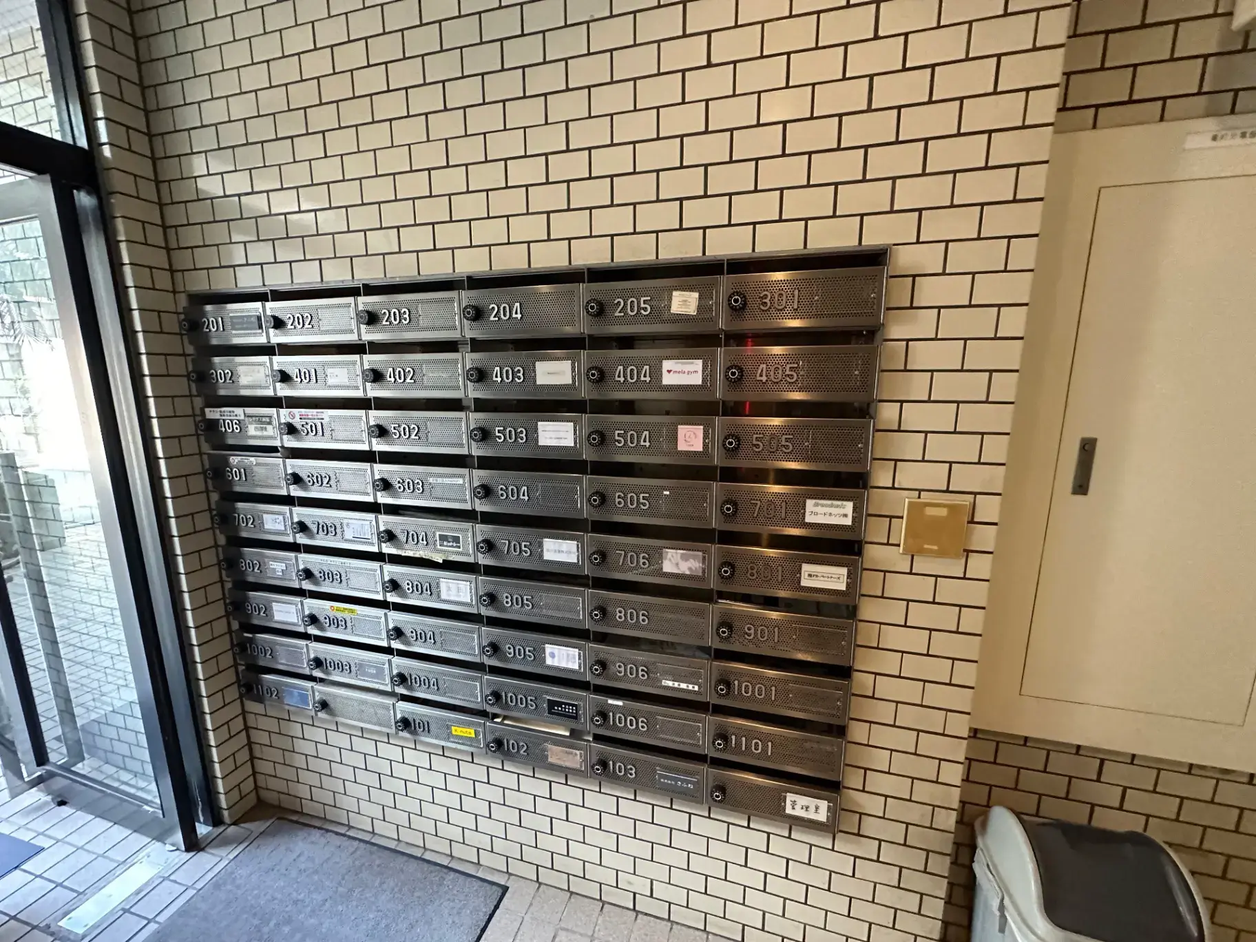 集合住宅のエントランスに設置された郵便受け、壁掛けタイプでナンバリングされた複数のメールボックス
