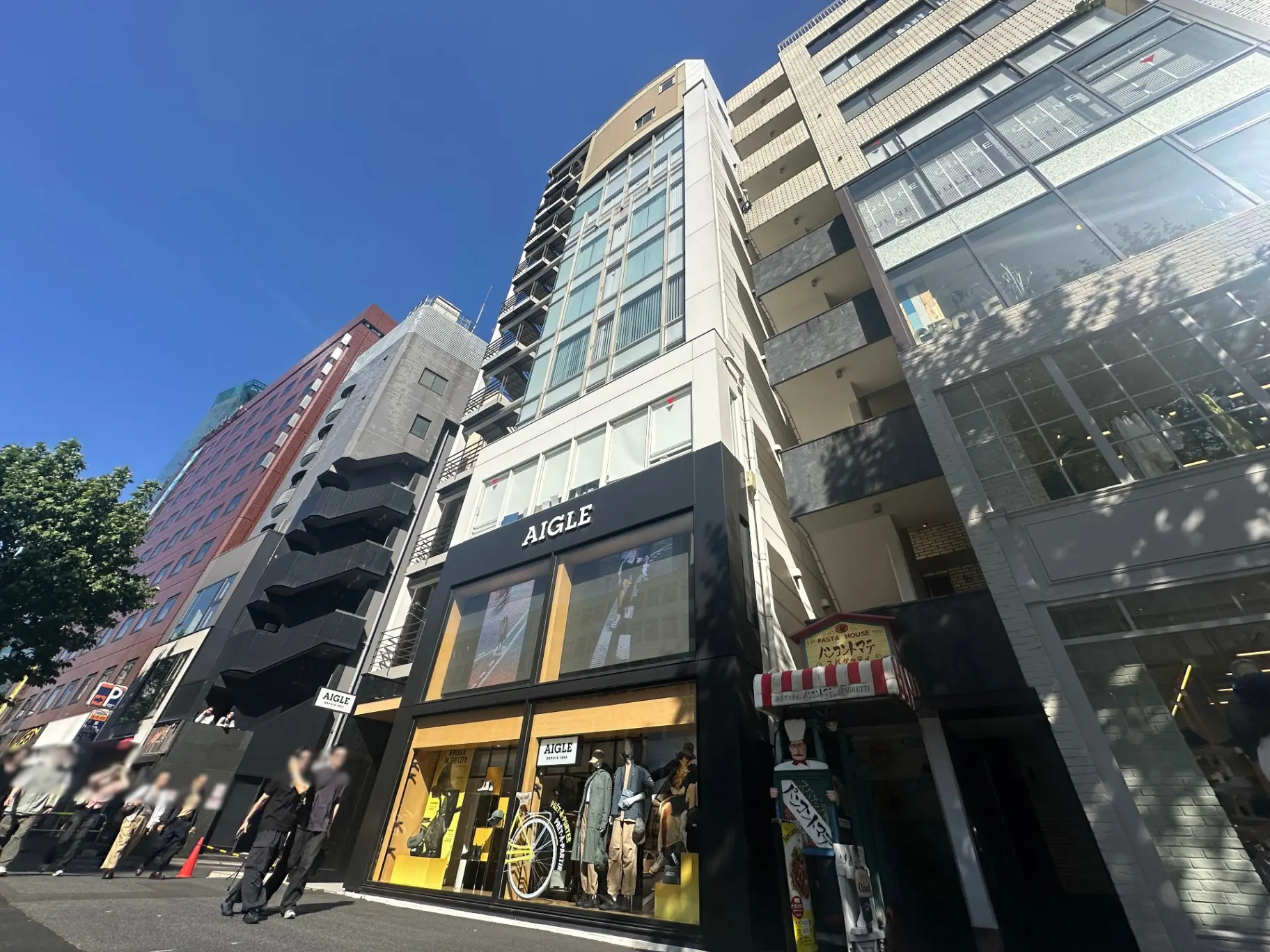 都会の通り沿いにあるAIGLEブランドの店舗、日差しが照らすモダンな外観デザイン