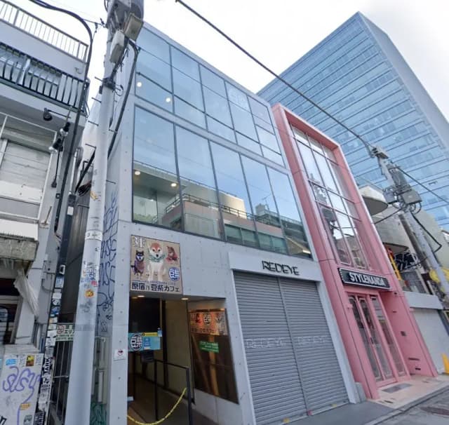 現代的なガラス張りの建物とピンク色のシャッター、周辺にはグラフィティアートが描かれた都市のストリートビュー