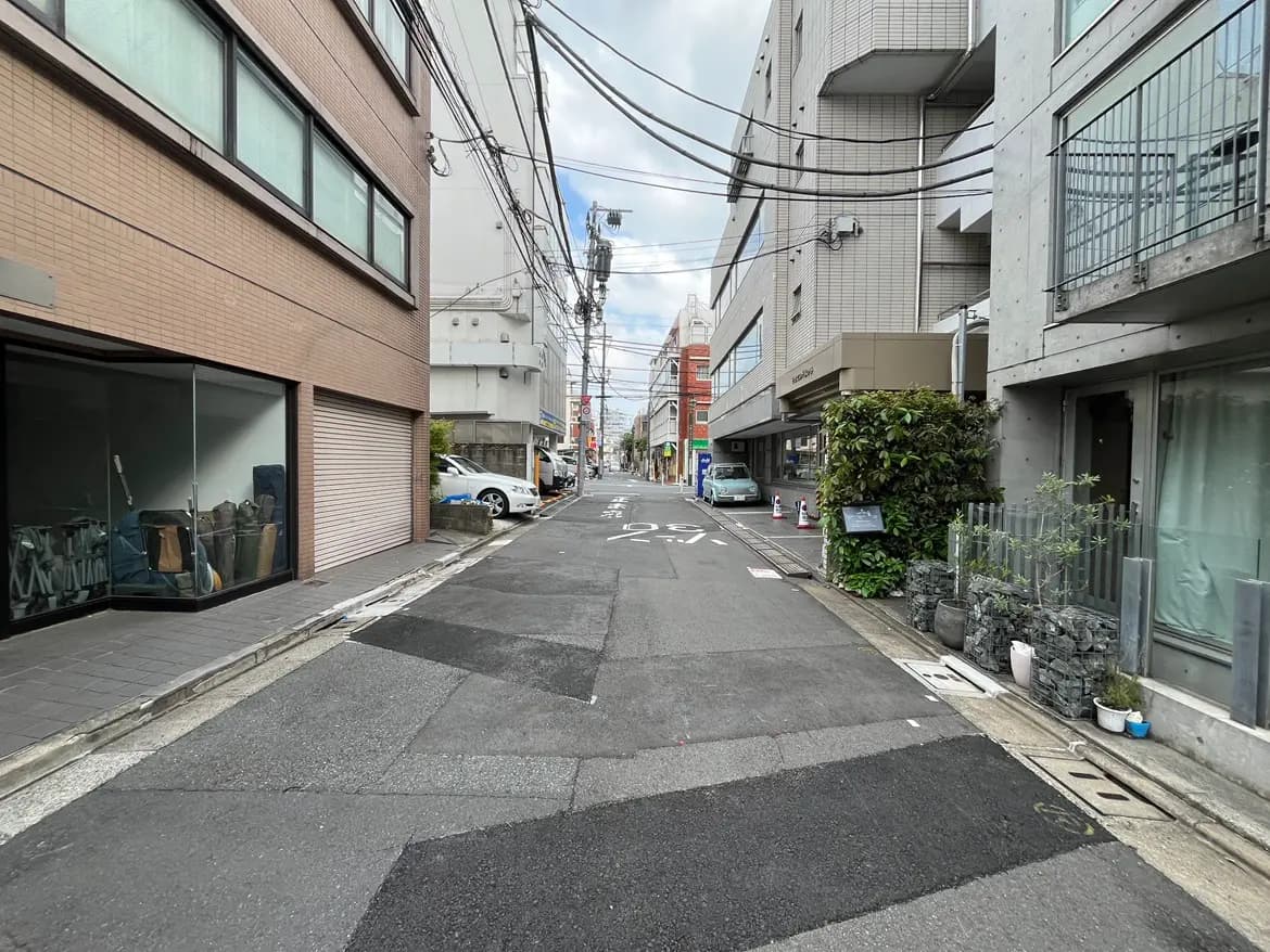 - 都市の静かな通り、レンガ造りの建物とガラス窓、電線が交差する風景、車が停まっている様子