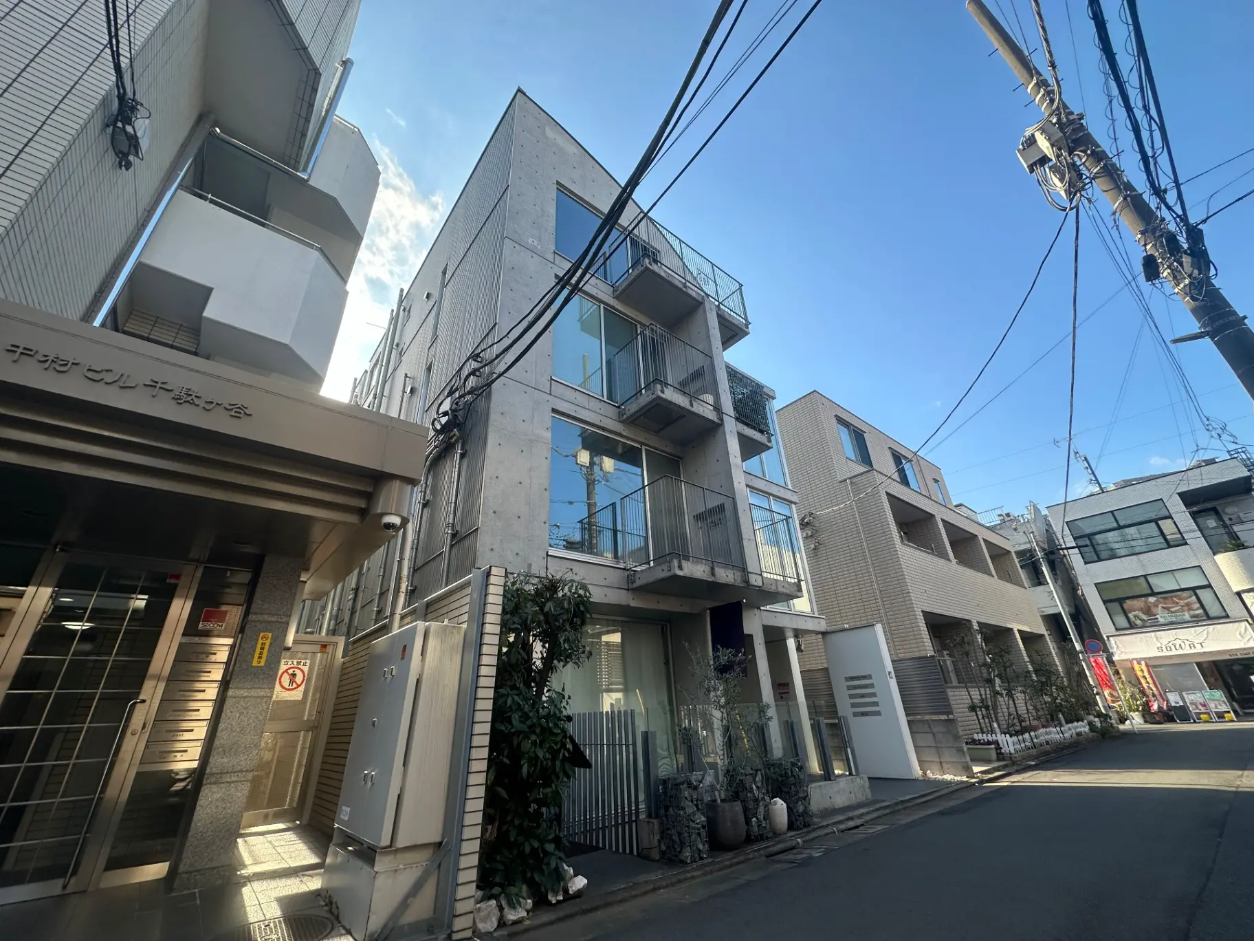 都会の中の近代的な建築物、明るい日差しが差し込む通り、電線が交差する景観