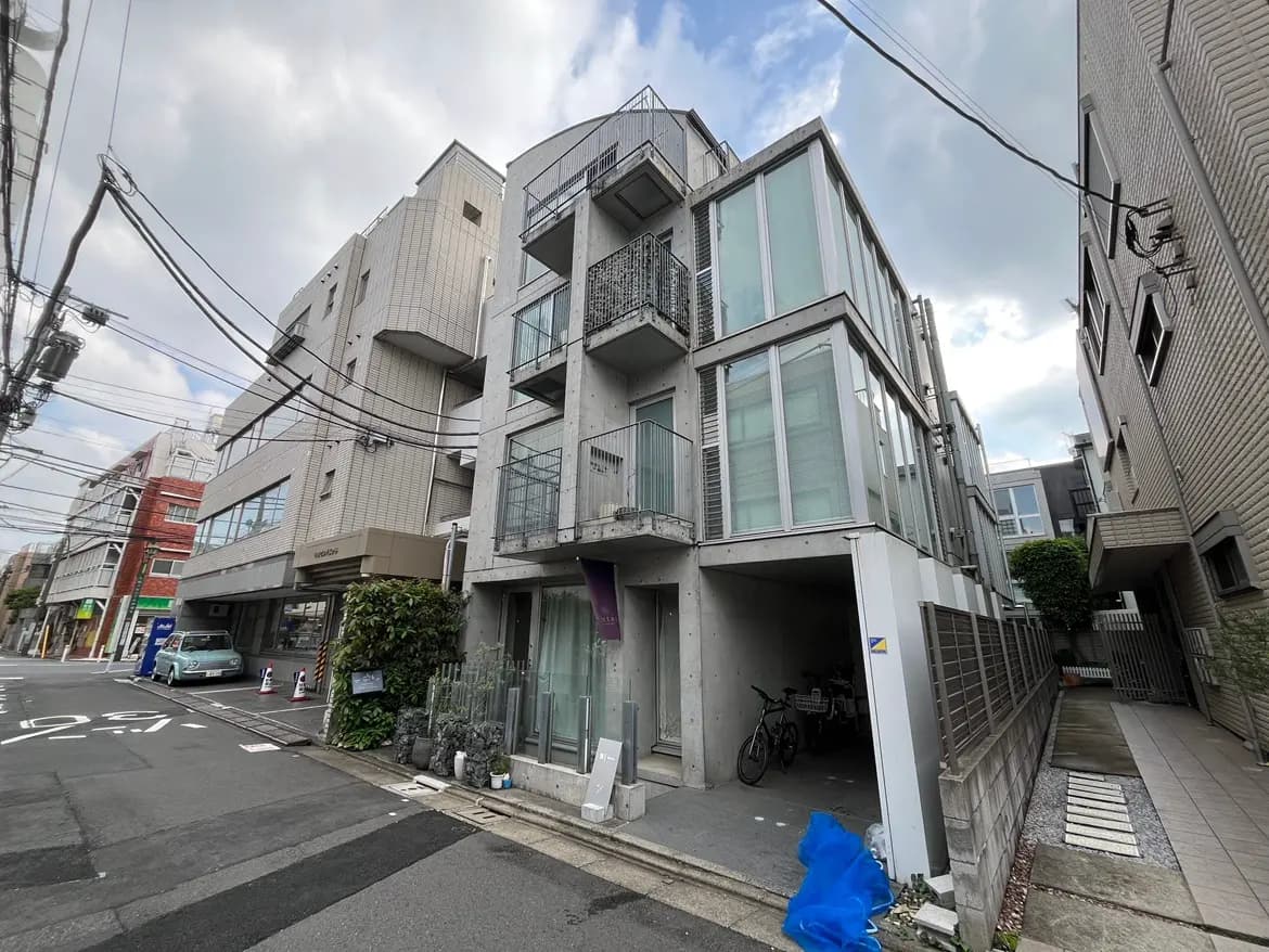 - コンクリートとガラスで構成されたモダンな建物、周囲に自転車や街の風景が広がる様子