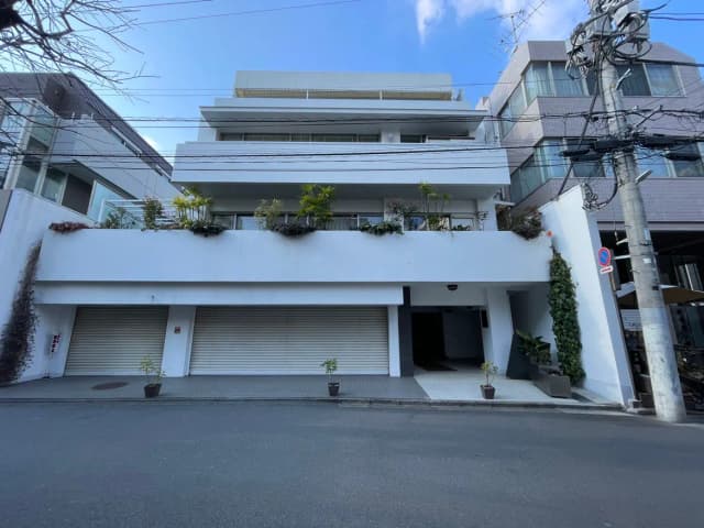 モダンな外観の都市型マンション、シャッター付きガレージと植栽のバルコニー