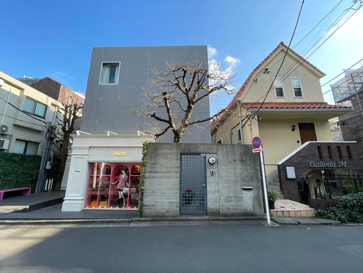 日差しが降り注ぐ都会の通りに面したモダンな建物と、伝統的なデザインの家、進入禁止の標識がある静かな住宅街