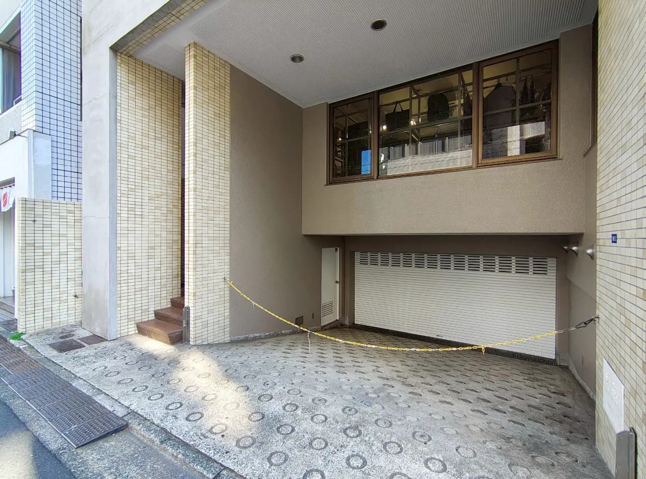 - 建物の入り口とガレージ、窓から自然光が差し込み、周囲にアクセントタイルが施された外観の写真