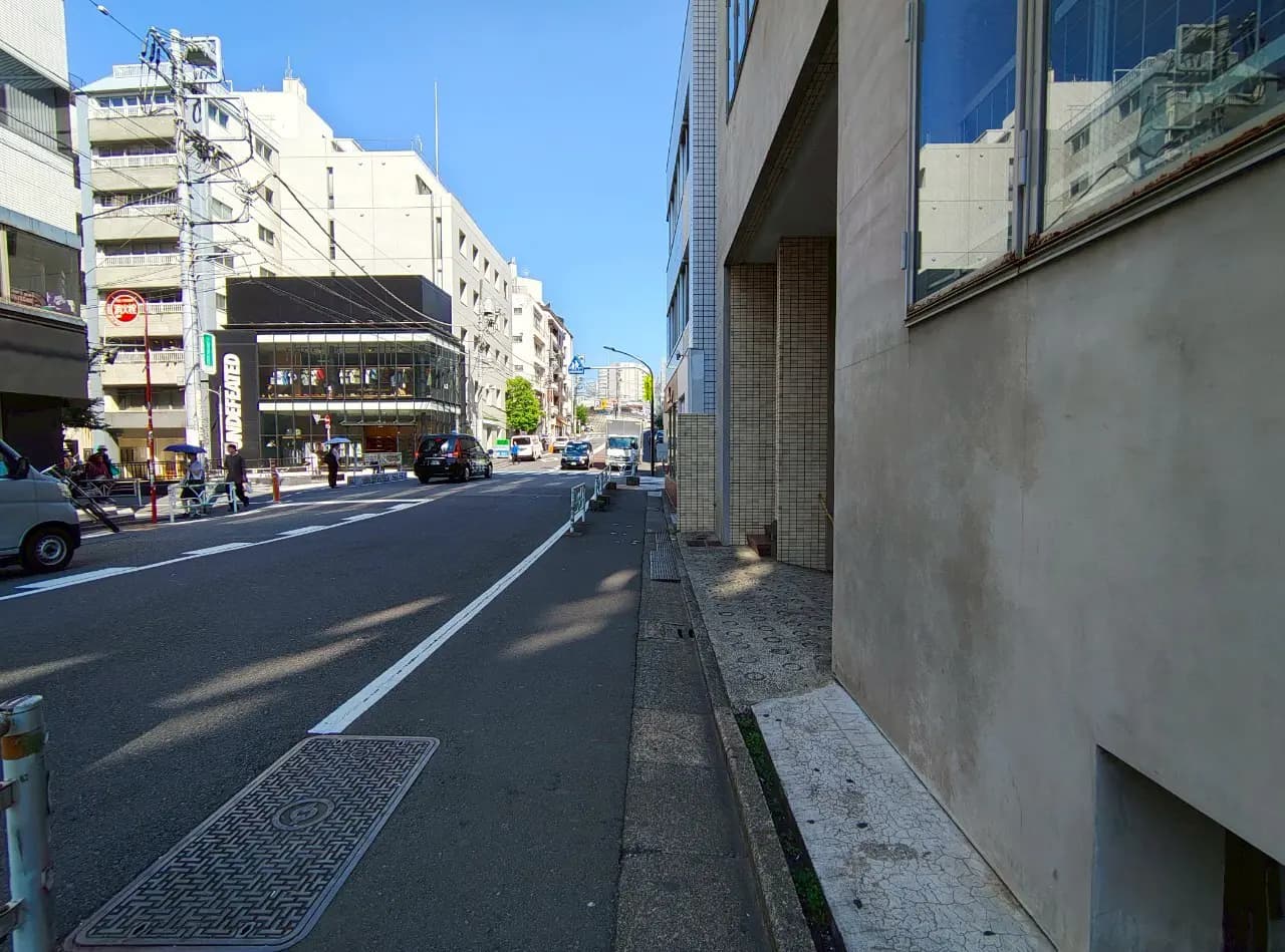 - 都市の通りの風景、右側には近代的な建物、左側には歩道と交通場面が広がるシーン